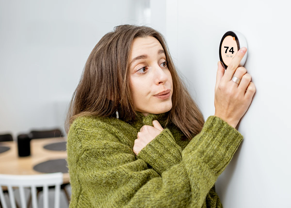 cold woman adjusting thermostat