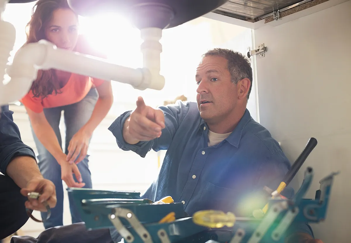 plumber talking to homeowner about pipe leak